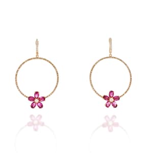Può includere: Un paio di orecchini a cerchio d'oro con un designo a forma di fiore rosa. I cerchi sono incastonati con piccoli diamanti e il fiore è fatto di pietre preziose rosa.