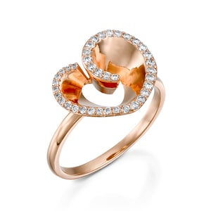 May include: A rose gold ring with a heart-shaped design. The heart is outlined with small diamonds and has a hollow center.