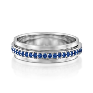 Puede incluir: Un anillo de banda de plata con una fila de zafiros azules alrededor del borde.