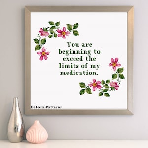 May include: A white cross-stitch pattern with a floral border and the text "You are beginning to exceed the limits of my medication."