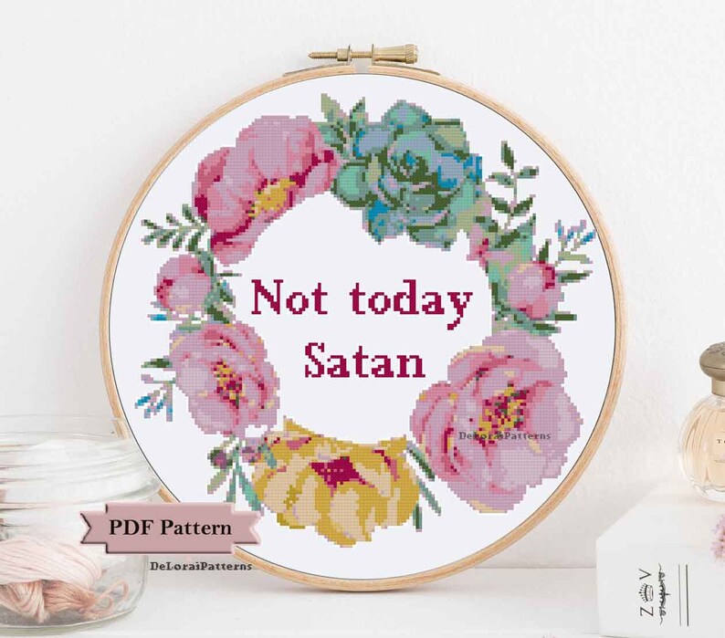 Może przedstawiać: Wz&oacute;r na haft krzyżykowy przedstawiający wieniec kwiatowy z tekstem "Not today Satan" w środku. Wieniec składa się z r&oacute;żowych i ż&oacute;łtych kwiat&oacute;w, zielonych liści i sukulenta.