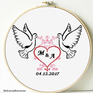 Puede incluir: Patrón de punto de cruz con dos palomas blancas con contornos negros, que se miran, con un corazón rojo en el centro. El corazón tiene las iniciales "M & A" y la fecha "04.12.2017" debajo.