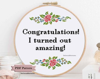 Puede incluir: Un aro de bordado blanco con un diseño floral y el texto "¡Felicidades! ¡Resulté increíble!" El aro está sobre una superficie blanca con un frasco de hilo y una botella de perfume.