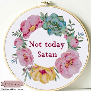 Może przedstawiać: Biały tamborek do haftu z wzorem wieńca kwiatowego i tekstem "Not today Satan" w kolorze czerwonym. Wieniec wykonany jest z r&oacute;żowych i ż&oacute;łtych kwiat&oacute;w oraz zielonych liści.