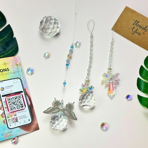 May include: DIY crystal suncatcher kit with instructions. The image shows three crystal suncatchers with angel and butterfly designs, along with loose crystals and a thank you card. The kit includes a phone displaying a QR code.