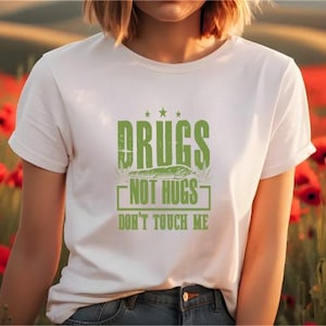 May include: White t-shirt with green text that reads "Drugs Not Hugs Don't Touch Me".