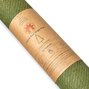May include: A brown paper tube with a green yoga mat inside. The tube has a label that says "4mm Eco Yoga Mat" and lists features like "3 Trees Planted", "Incredible Grip", and "Made From Natural Tree Rubber & Natural Jute".
