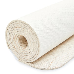 May include: A rolled up white yoga mat with a textured surface. The mat has a beige underside with a herringbone pattern.