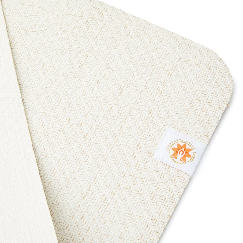 May include: A white yoga mat with a subtle herringbone pattern and a small orange logo that says "Complete  What  Yoga".
