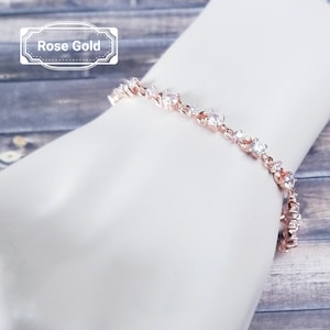 Pu&ograve; includere: Bracciale in oro rosa con una catena delicata e piccoli zirconi cubici trasparenti.
