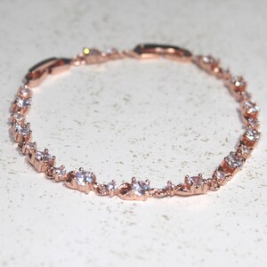 Pu&ograve; includere: Un braccialetto in oro rosa con una catena delicata e pietre di zircone cubico trasparenti.