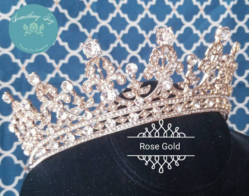 Puede incluir: Una corona de oro rosa con diamantes de imitaci&oacute;n transparentes. La corona est&aacute; sobre un fondo de terciopelo negro.