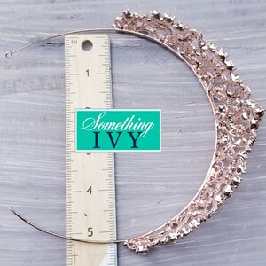 Puede incluir: Tiara de oro rosa con un dise&ntilde;o calado adornado con pedrer&iacute;a transparente. Se mide con una regla. El texto "Something Ivy" es visible.