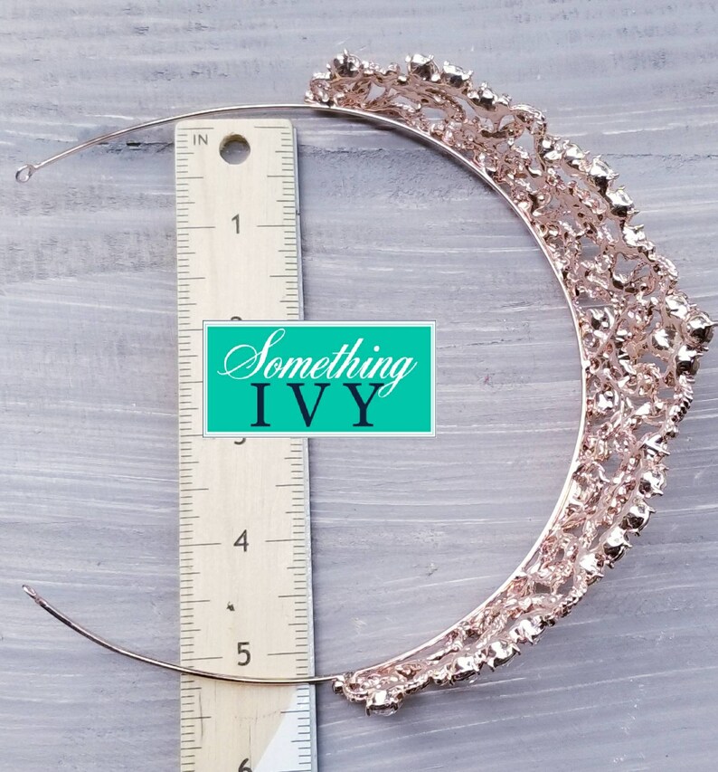 Puede incluir: Tiara de oro rosa con un dise&ntilde;o calado adornado con pedrer&iacute;a transparente. Se mide con una regla. El texto "Something Ivy" es visible.