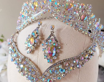 Puede incluir: Un conjunto de tiara, collar y pendientes de novia de plata con pedrería iridiscente. El conjunto se muestra en un maniquí de busto blanco.
