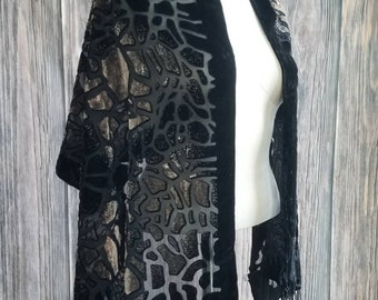 May include: Black velvet shawl with a geometric pattern and fringe. The shawl is draped over a mannequin.