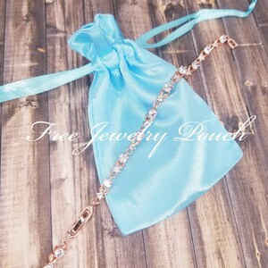 Pu&ograve; includere: Un braccialetto in oro rosa con pietre di zircone cubico trasparenti. Il braccialetto &egrave; su una pochette in raso blu chiaro con il testo "Borsa per gioielli gratuita".