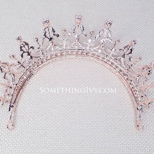 Puede incluir: Tiara de oro rosa con un delicado dise&ntilde;o floral y brillantes transparentes. La tiara es curva y tiene una parte superior puntiaguda.