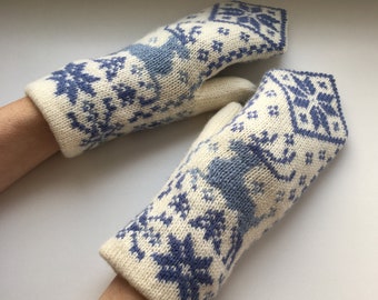 May include: A pair of white knitted mittens with a blue snowflake and reindeer pattern.
