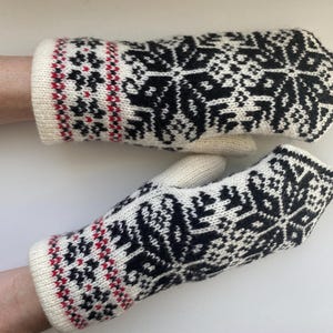 May include: Pair of white knitted mittens with a black and red snowflake pattern.