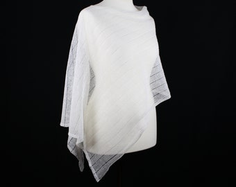 Può includere: Poncho bianco in crochet con una trama larga e aperta. Il poncho è drappeggiato su un manichino bianco.