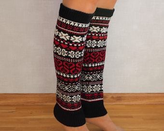 May include: Black and white leg warmers with a red and white geometric pattern. The leg warmers are knitted and have a black cuff.