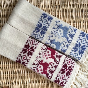 Könnte beinhalten: Zwei gestrickte Schals mit weißem Hintergrund und bunten geometrischen Mustern. Ein Schal hat ein blaues Muster und der andere ein rotes Muster.