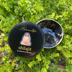 May include: A black jar with a black lid containing a dark brown substance. The jar has a label with the text "Mahavatar" and "shilajit harvested from the Himalayas".