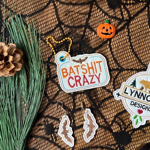 May include: A set of Halloween-themed embroidery designs featuring a bat, a bear, and a pumpkin. The designs are on white fabric with colorful embroidery thread. The designs are for sale on Etsy.