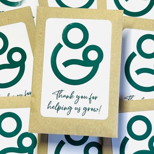 May include: Thank you for helping us grow! A stack of brown cards with a green logo of two circles, one inside the other, with a smile.