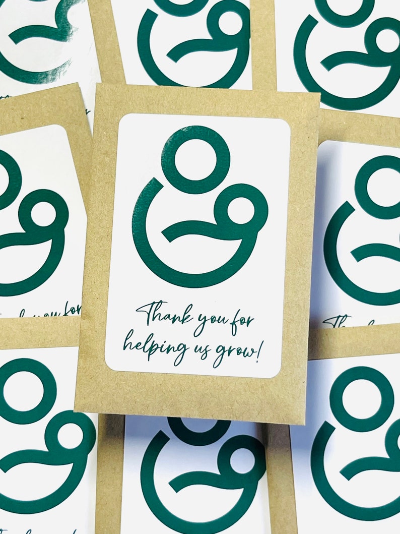 May include: Thank you for helping us grow! A stack of brown cards with a green logo of two circles, one inside the other, with a smile.