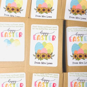 May include: Six brown paper bags with white labels. Each label features a colourful illustration of Easter eggs with sunflowers and the text "Happy Easter" and "From Mrs Lowe". The labels also include the text "Plant these sunflower seeds for the butterflies and bees!"