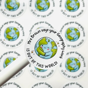 May include: Round white stickers with a green and blue cartoon earth hugging itself. The text on the sticker says "Mrs. Brown says your Geography work is out of this world!"