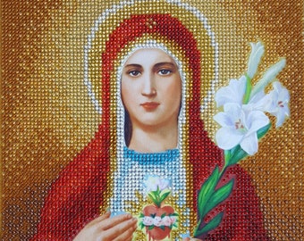 Puede incluir: Una representación de cuentas de la Virgen María con una túnica roja, un velo blanco y un corazón con espinas. Ella sostiene un lirio blanco en su mano derecha.