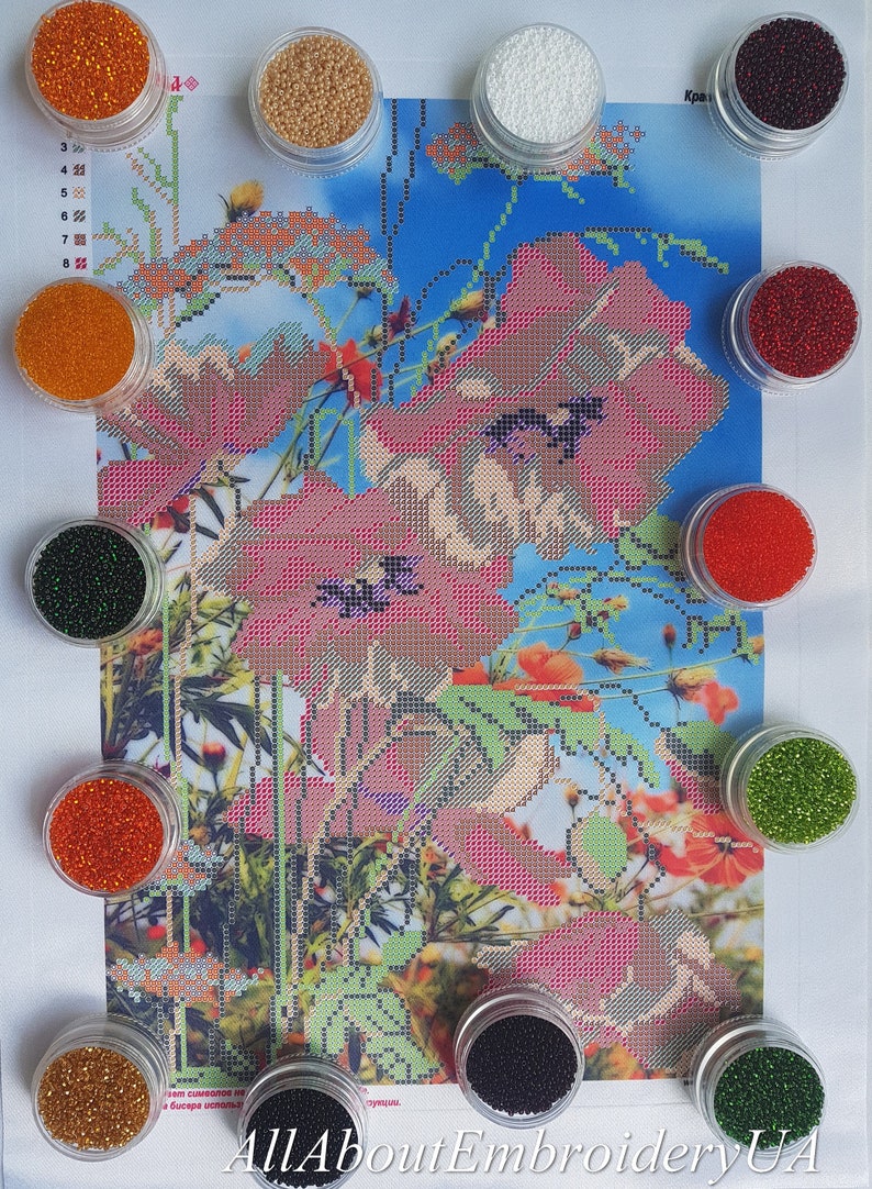 May include: Assortment of small containers filled with colorful beads, used for diamond painting. The beads are in various colors, including red, orange, green, black, and white. The containers are arranged around a printed image of red poppies.