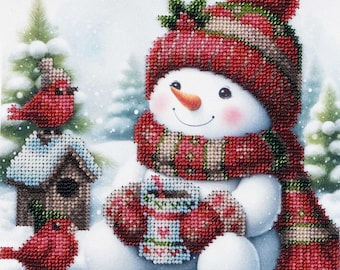 Puede incluir: Un muñeco de nieve con un gorro y una bufanda rojos y verdes sostiene una taza de chocolate caliente. Dos cardenales rojos están posados en una casita de pájaros en el fondo nevado.