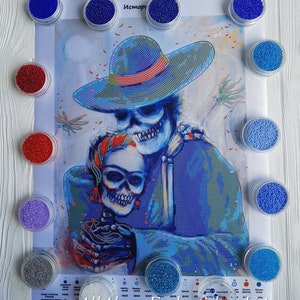 May include: A close-up of a beaded embroidery kit featuring two skeletons embracing. The skeletons are wearing colourful clothing and hats. The kit includes a variety of colours of beads in small containers.
