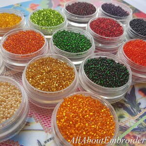 May include: Assortment of small, round, colorful beads in clear containers. The beads are arranged in rows and are various colors, including white, green, orange, red, and black.