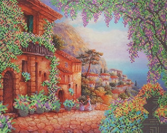 May include: A painting of a quaint European village with a stone building covered in green vines. The building has a balcony and a door. The village is nestled in a valley with mountains in the background. The sky is blue and there are clouds in the sky. The painting is framed with a border of green vines.
