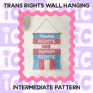 Op de afbeelding: Een wandkleed met de tekst "TRANS RIGHTS ARE HUMAN RIGHTS" in witte letters. Het wandkleed is in de kleuren van de transgender vlag: blauw, roze en wit. De woorden "TRANS RIGHTS WALL HANGING" en "INTERMEDIATE PATTERN" zijn ook zichtbaar.