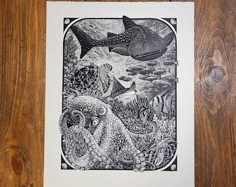 May include: Black and white woodcut print depicting an octopus, a turtle, a manta ray, and a school of fish. The print is framed with a decorative border.