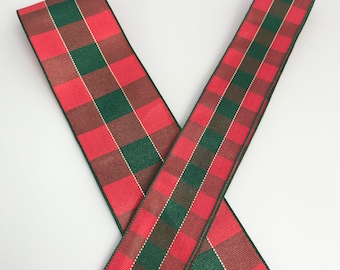 May include: Red and green plaid ribbon with a gold thread running through it. The ribbon is folded in an X shape.