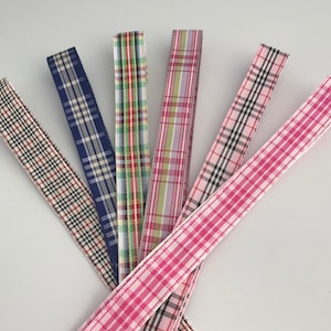 May include: Six different plaid ribbon trims in various colours, including pink, blue, green, and white.
