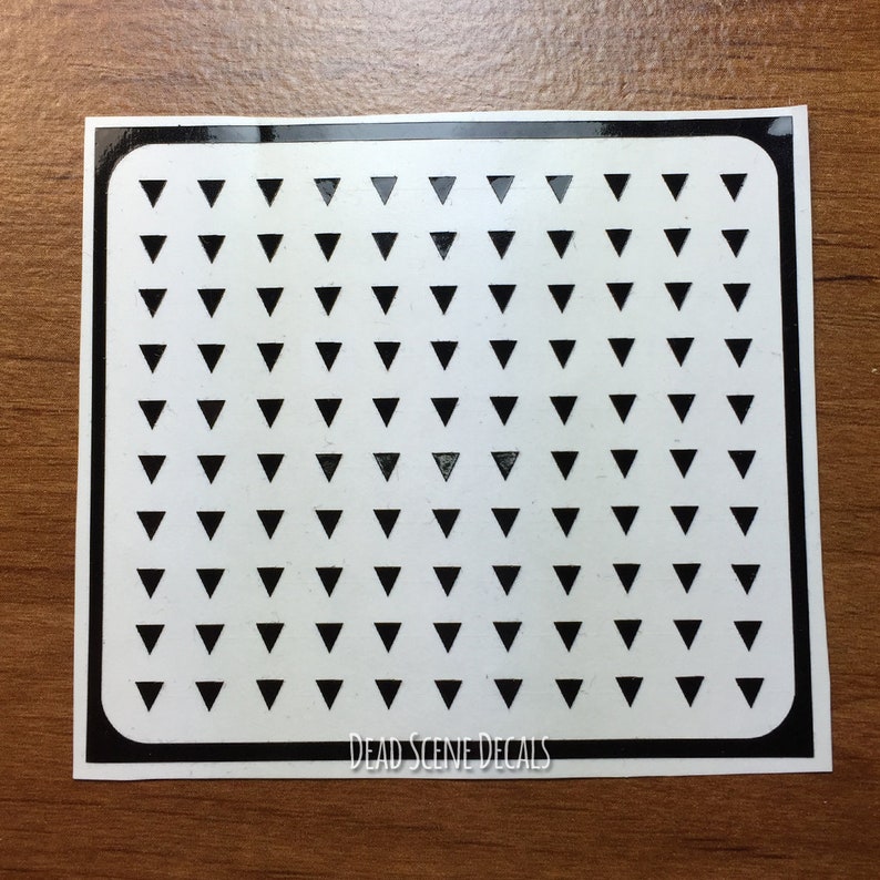 May include: Black and white sticker sheet with a pattern of small black triangles on a white background. The sticker sheet has a black border and the text "DEAD SCENE DECALS" at the bottom.