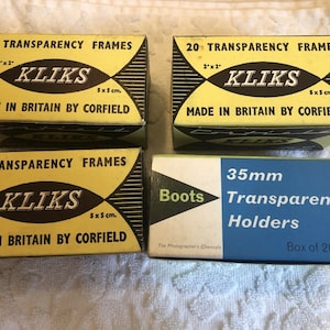 May include: Four boxes of 2" x 2" transparency frames. Three boxes are yellow with black text and say "20 Transparency Frames" and "KLiKS" with the brand name "Corfield". The fourth box is blue with white text and says "Boots 35mm Transparency Holders" and "Box of 20 6/8".