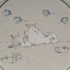 May include: A white cat with brown spots is lying on its back with its paws in the air.  There are five blue and yellow fish swimming around the cat.