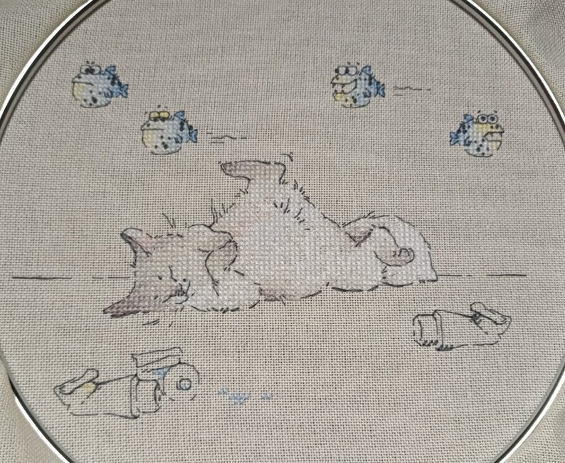 May include: A white cat with brown spots is lying on its back with its paws in the air.  There are five blue and yellow fish swimming around the cat.