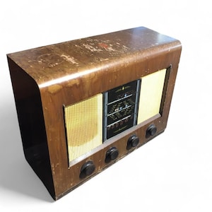 May include: A vintage wooden radio with a black face and gold speaker grilles. The radio has three knobs on the front and is in good condition.