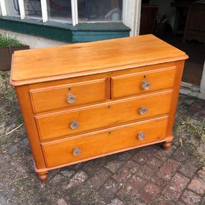 May include: A four-drawer wooden chest with a light brown finish. The chest has glass knobs on each drawer.