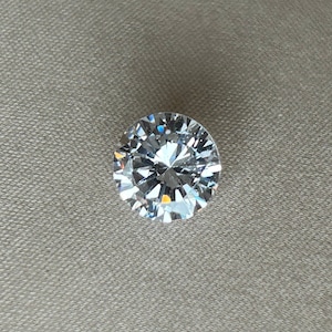 May include: A clear round diamond gemstone with many facets.